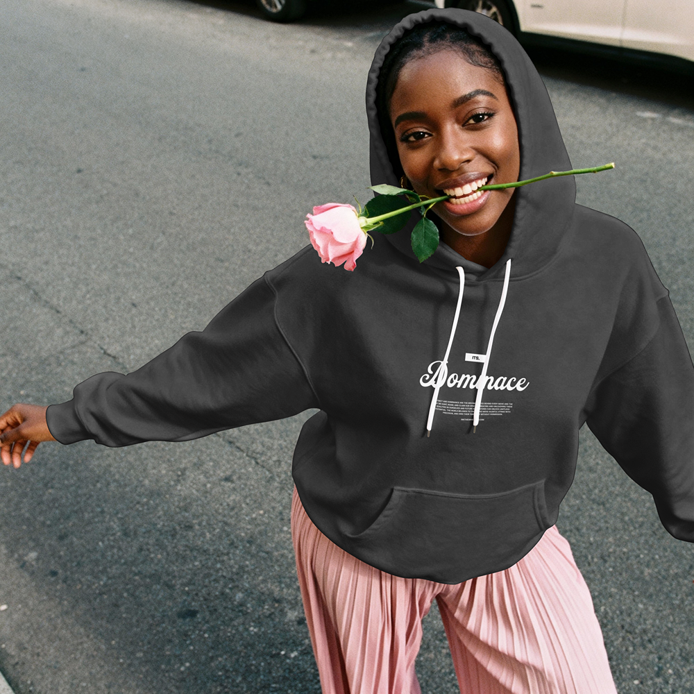 Woman in black 'Dompace' hoodie holding pink rose, streetwear style with pink pleated pants