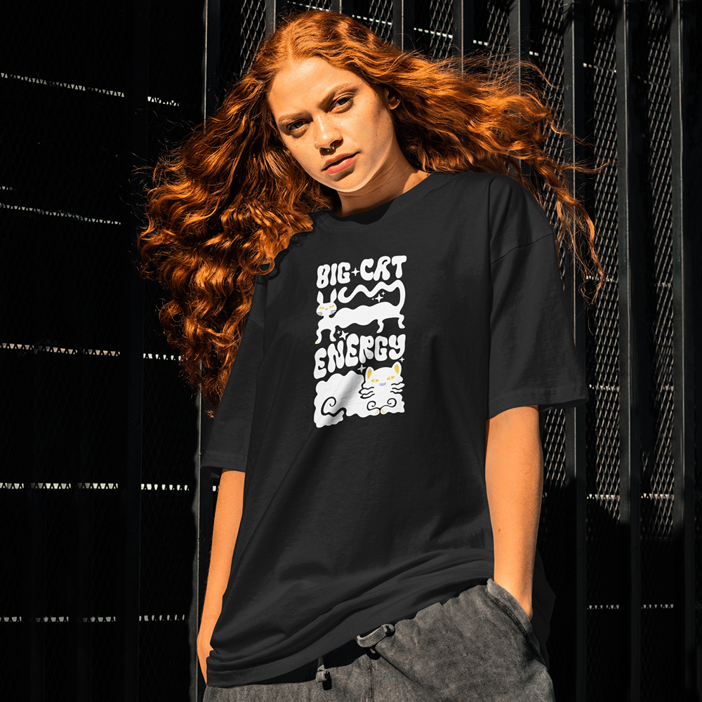 Woman wearing black graphic tee with 'Big Cat Energy' cat design, streetwear style