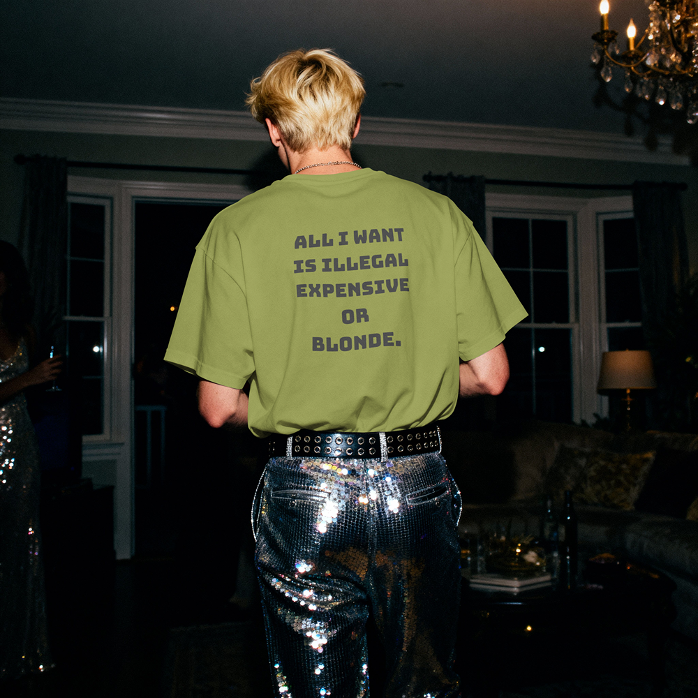 Olive graphic tee with bold text 'All I Want Is Illegal Expensive Or Blonde' worn with sequin pants at party