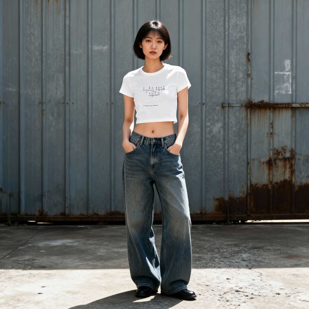 White crop t-shirt with Arabic script graphic, paired with wide-leg jeans, urban streetwear style